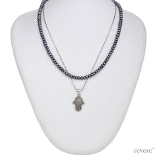 Load image into Gallery viewer, This elegant strand of dark grey pearls is beautifully complimented by a sparkling silver chain and hand shaped charm pendant. &quot;Khamsa&quot; represents blessings, power and strength and is believed to be a sign of protection against the evil eye. 
