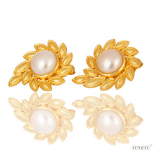 Load image into Gallery viewer, &quot;Anamitra&quot; in Sanskrit means the sun. The &quot;Anamitra&quot; stud earrings feature a beautiful sun shape or star burst shape with leaves embellished around a white freshwater pearl crafted with gold plated brass.
